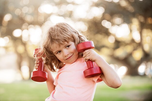 Sporty activity. Boy workout with dumbbell in park. Kid sport. Child exercising outdoor.