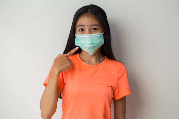 Sporty asian girl wearing medical mask to protection covid-19  posing on the white background