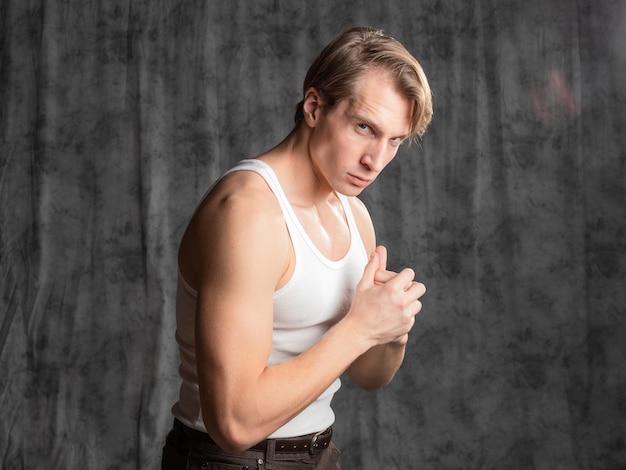 A sporty and athletic guy in a white tshirt boxing a young man in a vintage outfit posing in a studi