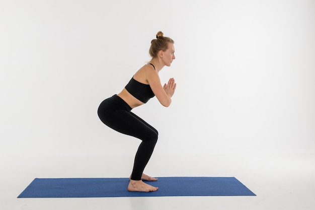 Sporty attractive young woman doing yoga practice on white background. Kursiasana.