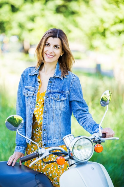 Sporty beautiful girl in a denim jacket on a retro motor scooter