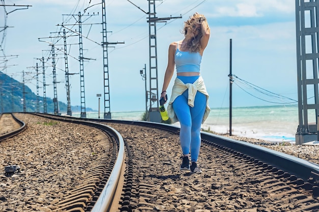 Фото Спортивная красивая девушка бегает на свежем воздухе вдоль железной дороги