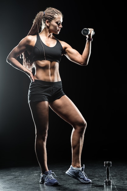 Sporty beautiful woman with dumbbells makes fitness exercising