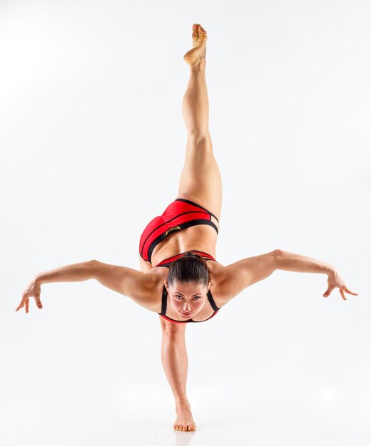 Sporty beautiful young woman practicing yoga doing lunge exercise Revolved Side Angle Pose working out wearing red and black sportswear studio full length isolated white background