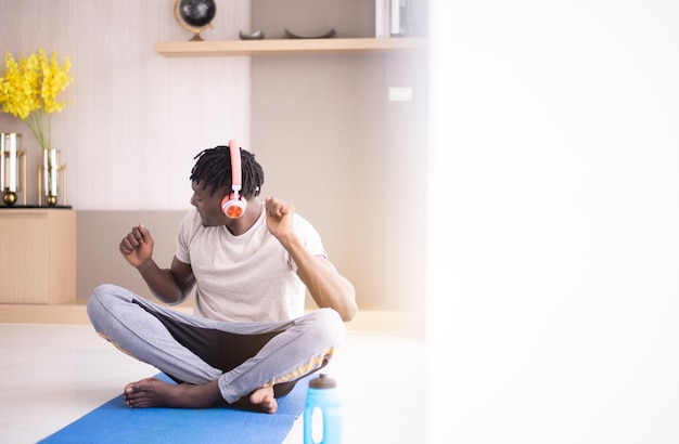 Photo sporty black man listening to music with headphone and workout at home