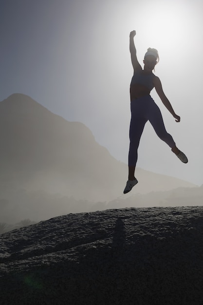 Sporty blonde on the beach on a rock jumping