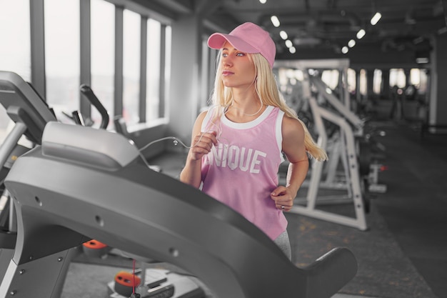 Sporty blonde woman exercising on treadmill in gym