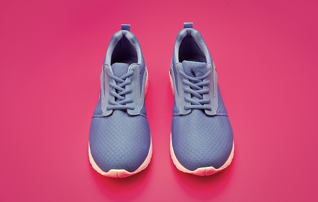 Sporty blue sneakers shoes on pink background shoe store\
shopping concept