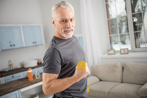 Sporty body. Delighted bearded man expressing positivity while doing sport and posing on camera