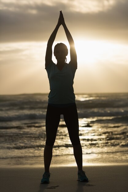 Sporty brunette stretching on the beach 