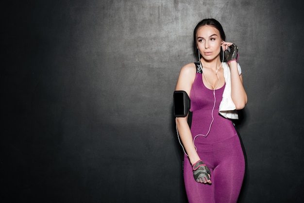 Sporty brunette woman listening music with earphones and looking away