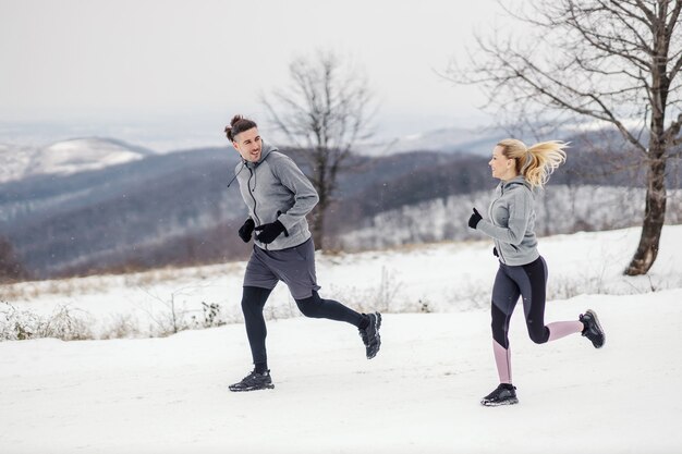 Фото Спортивная пара работает вместе на природе на снегу зимой. отношения, здоровые привычки, зимний фитнес