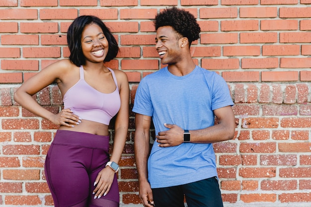 Sporty couple standing by a brick wall