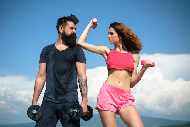 Sporty couple working out with dumbbells on sky background healthy lifestyle concept beautiful attra