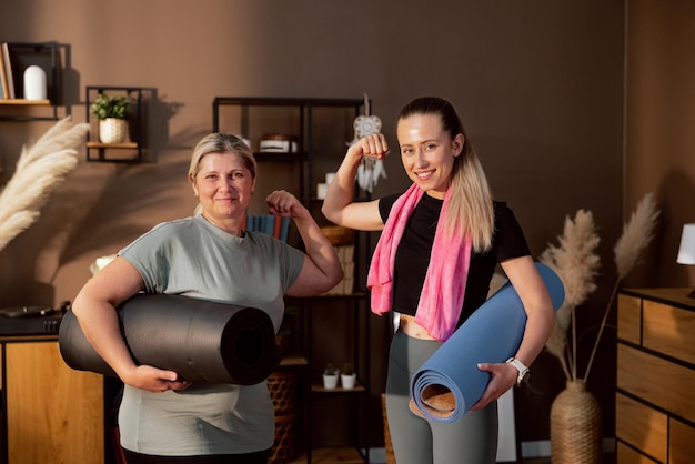 Sporty elderly mother and young charming daughter having fun together after training at home