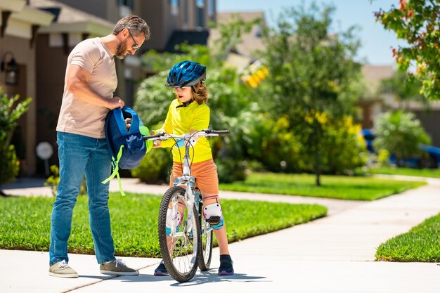 Sporty family father and son riding bike on a park child in safety helmet riding bike on summer day