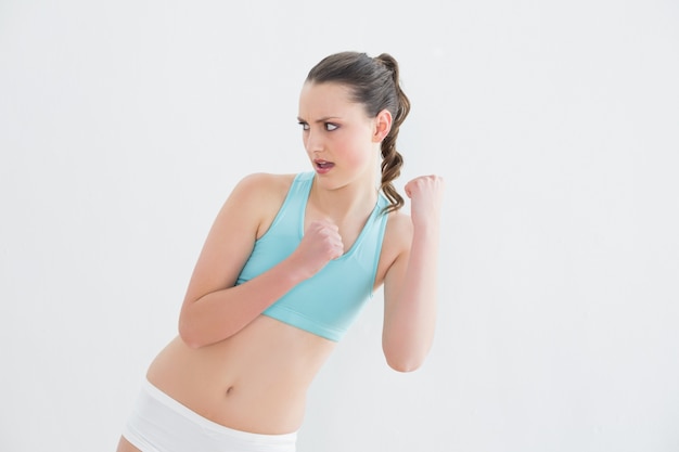 Sporty fit woman clenching fists against wall