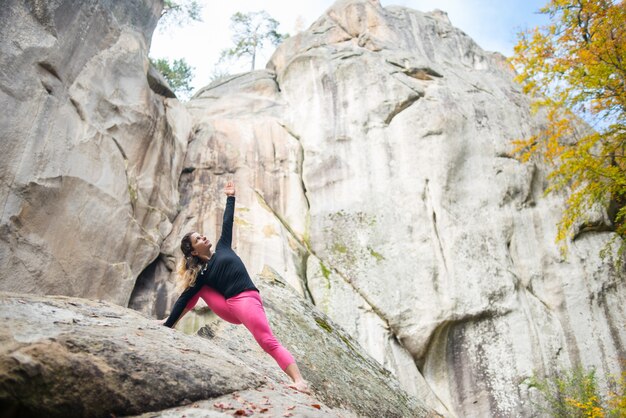 Photo sporty fit woman is practicing yoga on the boulder in the nature