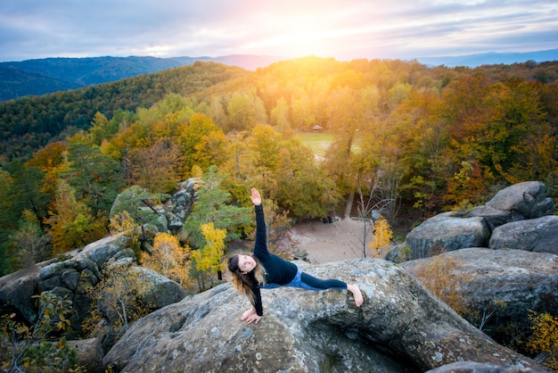 Photo sporty fit woman is practicing yoga on the top of the mountain