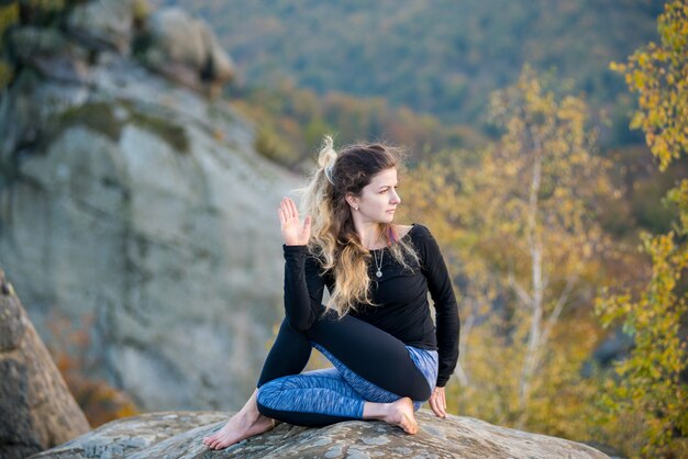 Sporty fit woman is practicing yoga on the top of the mountain