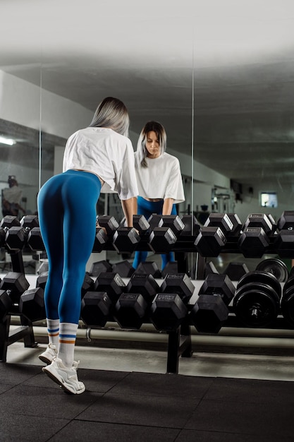 Sporty fitness girl is posing at the dumbbells in the gym