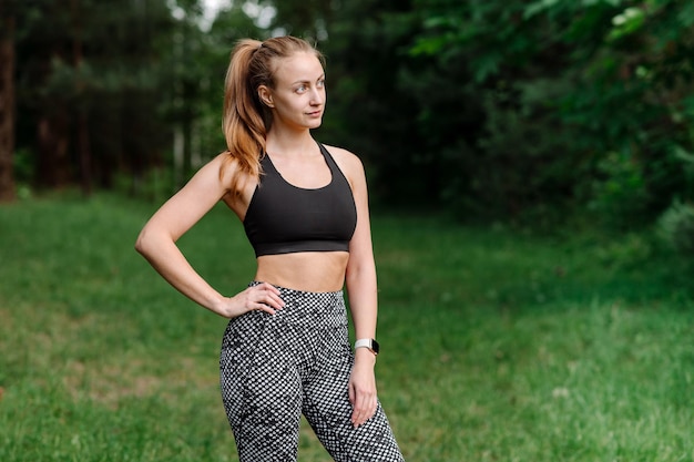 Sporty fitness woman in sportswear posing outdoors in the park