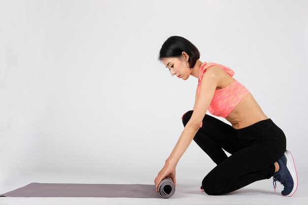 Sporty fitness woman in sportswear with yoga mat on white