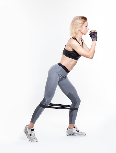 Sporty girl doing lunge exercise isolated on white background