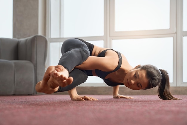 Sporty girl doing yoga pose indoors