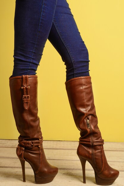 Sporty girl standing in brown high-heeled boots and jeans