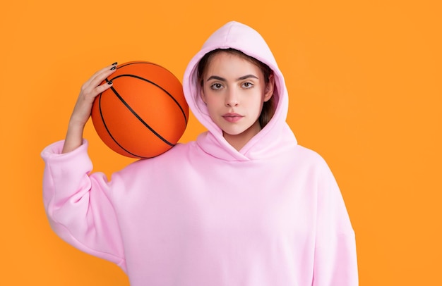 sporty girl student with basketball ball on yellow background