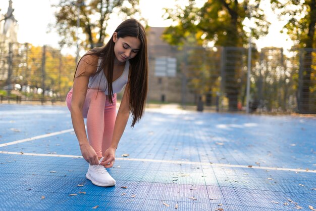 スニーカーで靴ひもを結ぶスポーティな女の子