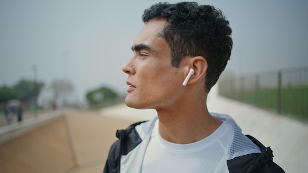 sporty guy listening music in earphones closeup confident fit athlete training