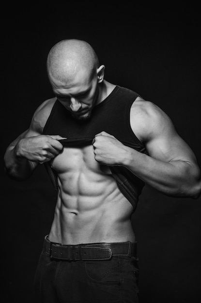 Sporty guy posing in the Studio on the background. Sports, beauty, black and white photography.