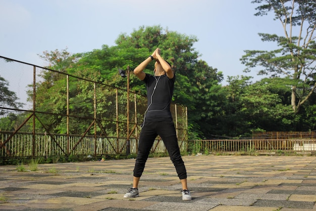 Sporty guy wearing earphones warming up before jogging running workout