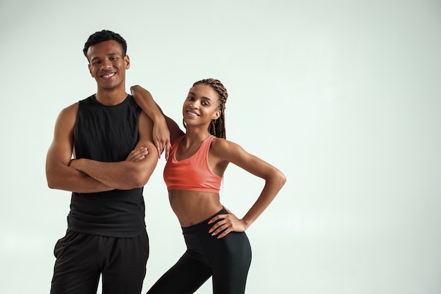 カメラを見て、笑顔でスポーツウェアのスポーティで健康的な若いアフリカのフィットネスカップル