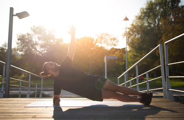 Sporty jonge man doet zijplank oefening tijdens het trainen buiten