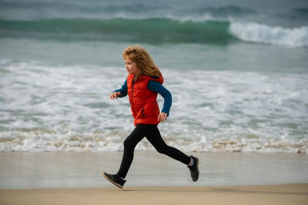 Sporty kid running in nature happy boy run to the sea child have fun on beach run by sea water pool