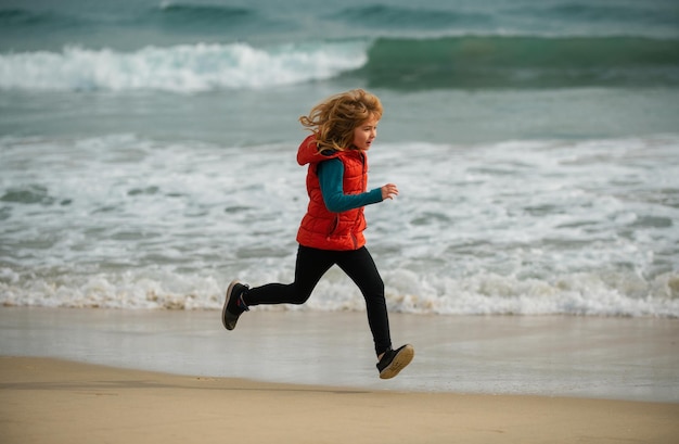 Sporty kind loopt in de natuur kleine jongen kind loopt langs de oceaan kind loopt op het zandstrand