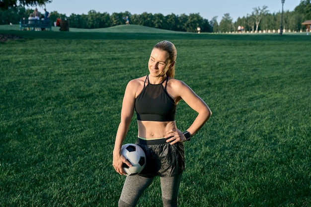 Sporty lady athletic beautiful middle aged woman soccer player smiling and holding the ball while