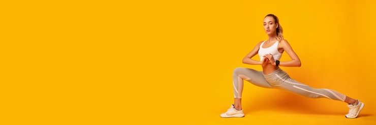 Photo sporty lady doing deep lunge exercise stretching legs over yellow background studio shot panorama