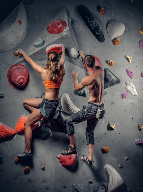 Sporty male and female climbing on a climbing  wall.