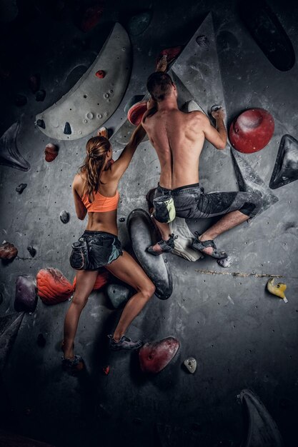 Sporty male and female climbing on an indoor climbing wall.