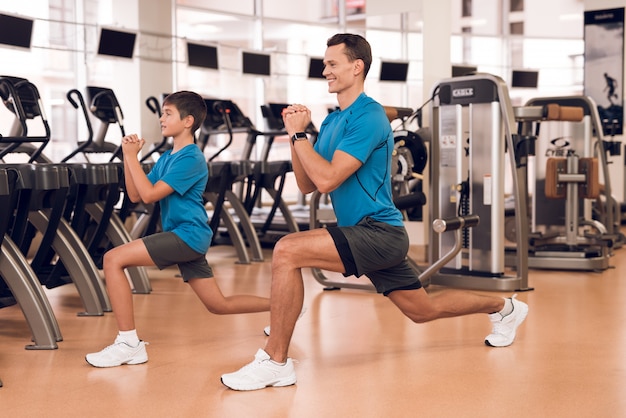 スポーティな男と現代のジムでトレッドミルの近くの少年