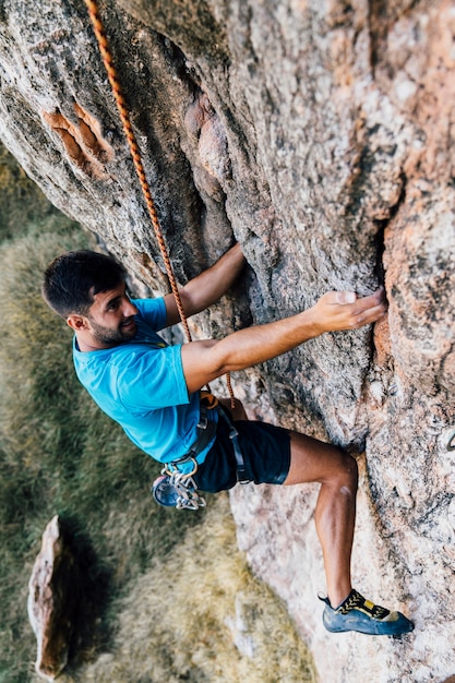 Photo sporty man climbing on rock