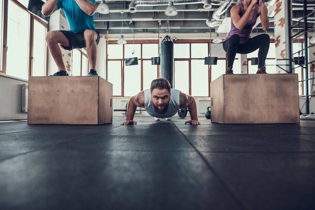 Sporty Man Doing Push Ups Between Two Athletes.