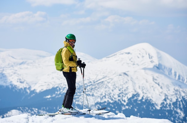 Sporty man enjoying skiing day and spectacularly view mountain landscape under blue sky