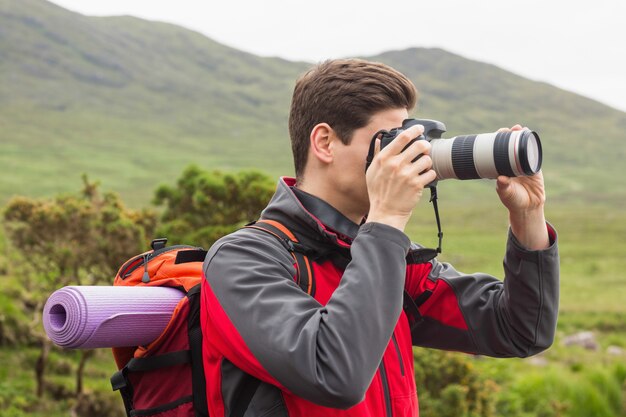 Sporty man on a hike taking a photograph