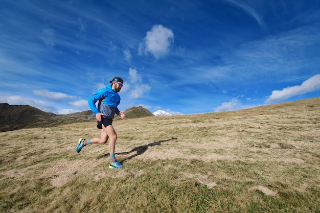 スポーティな男は大きな山の牧草地を実行します