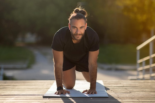 Photo sporty man standing in all fours position while exercising outdoor